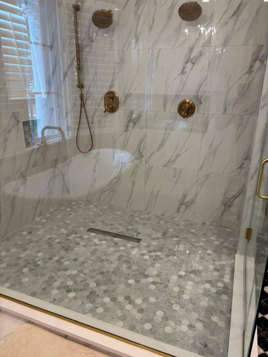 Finished walk-in shower with marble-look tile and brass fixtures