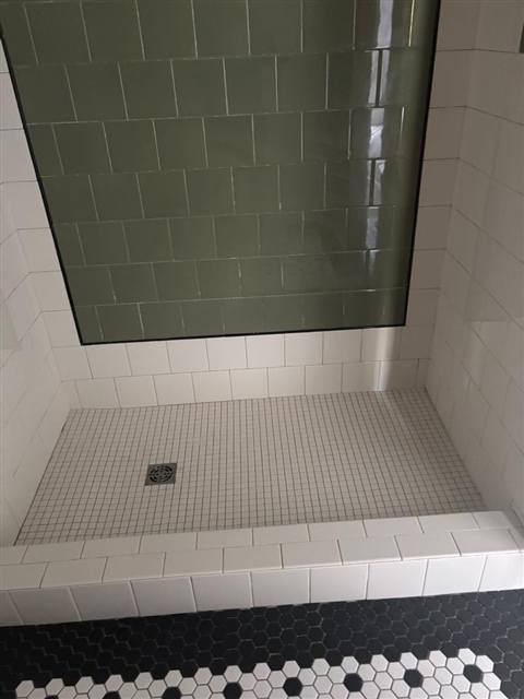 Subway tile shower with green glass accent